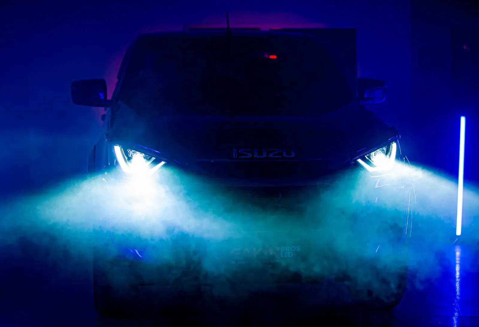 Vehicle headlights cutting through blue-lit smoke