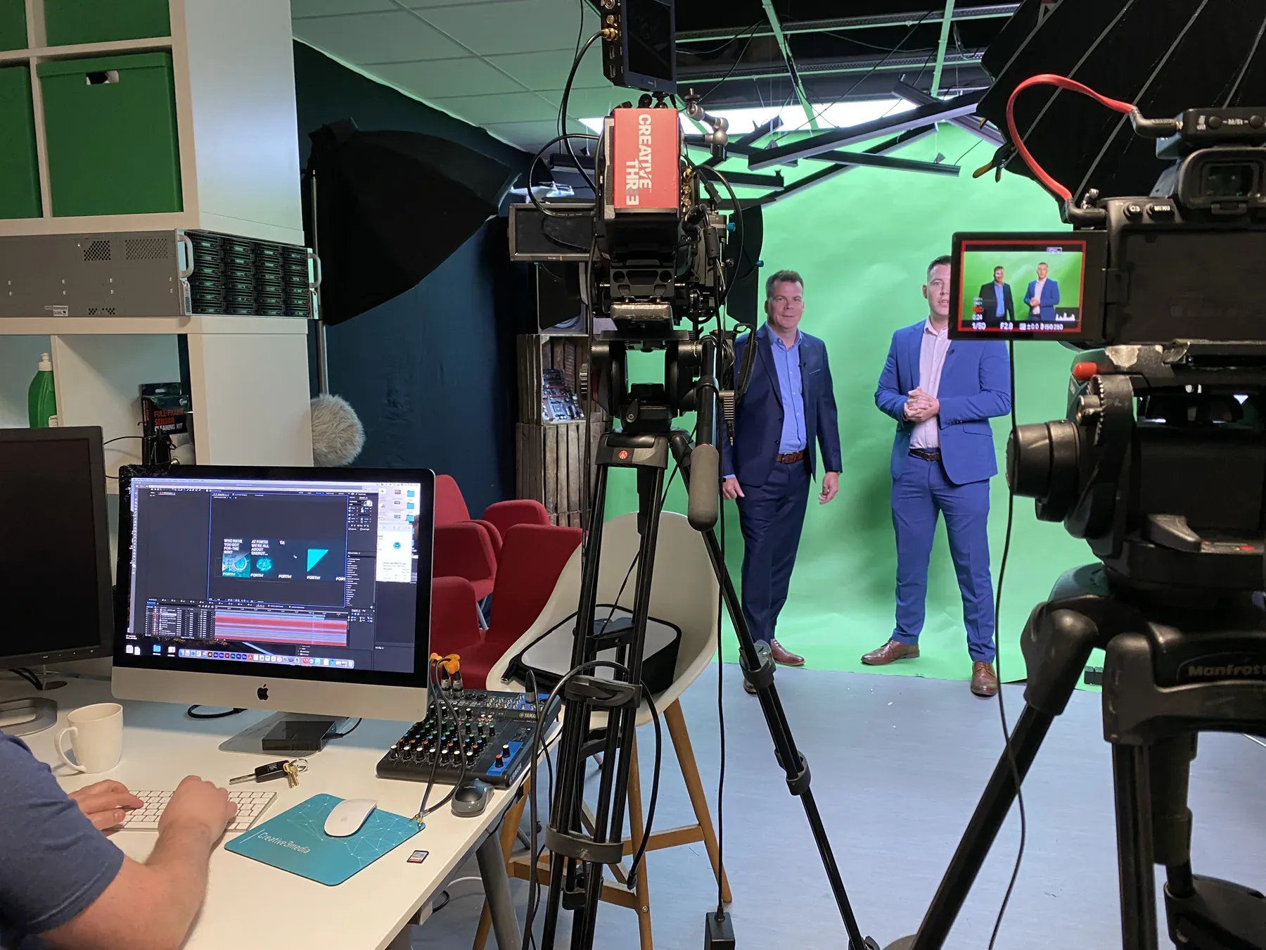 Camera view of presenters on a green-screen stage