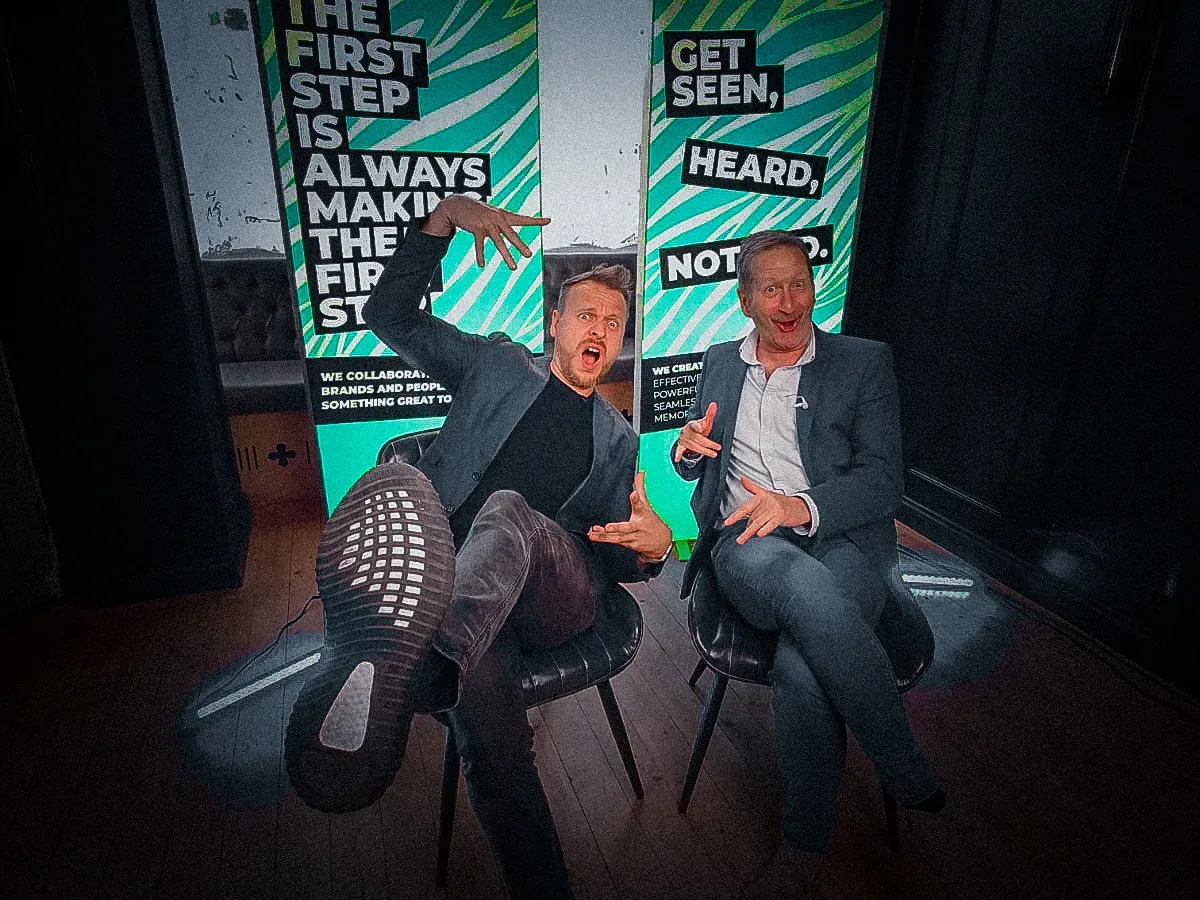 Two people chatting on a sofa in a colourful studio