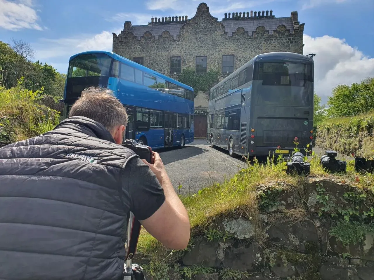 Photographer shooting buses outside a castle
